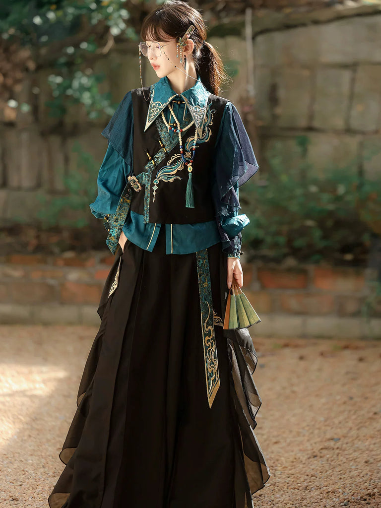 Woman wearing a traditional outfit with a blue top and black skirt in an outdoor setting.