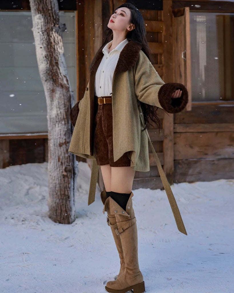 Woman in winter clothing standing in the snow next to a wooden building.