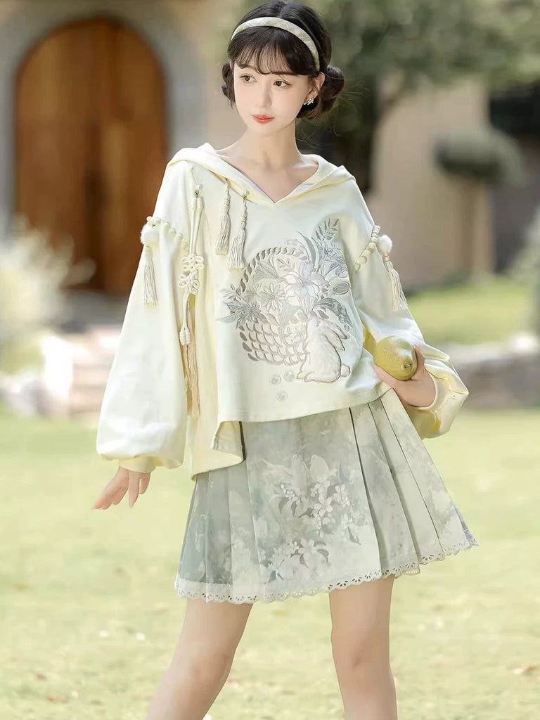 Woman in a light-colored outfit with floral patterns standing outdoors.