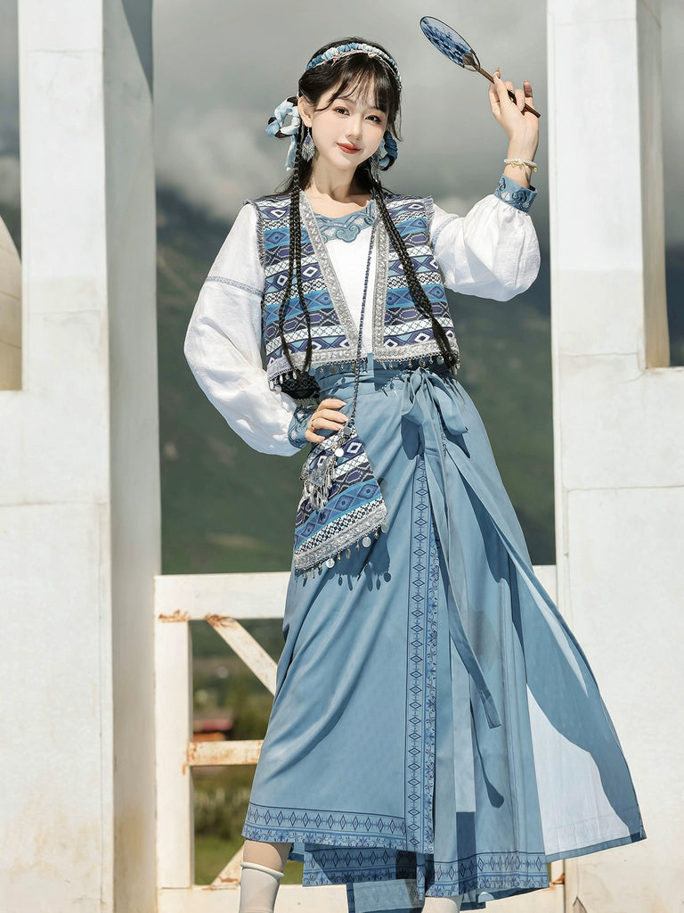 Person wearing a traditional outfit with a blue skirt and patterned top, holding a fan.